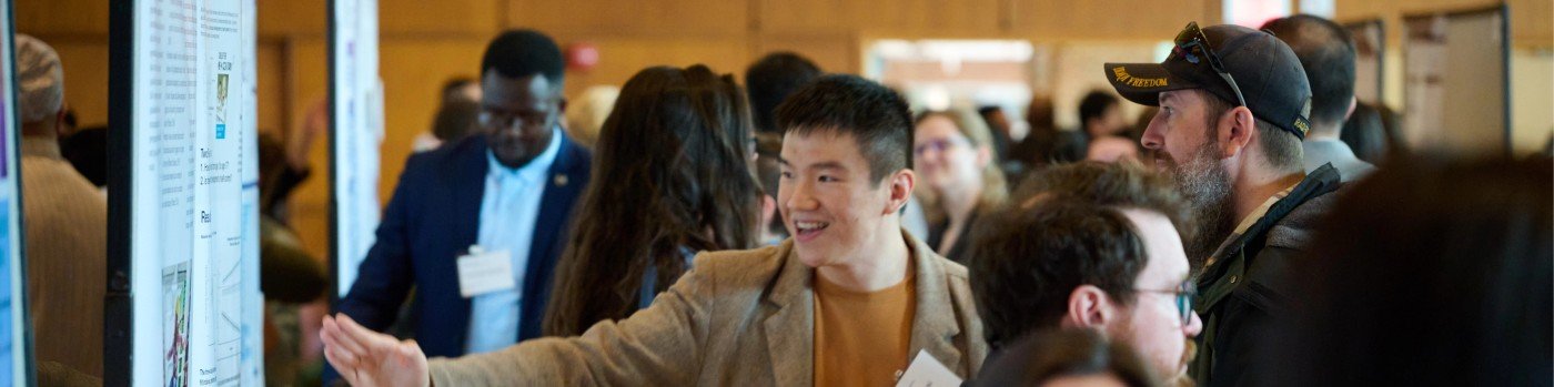 Siyang Ni explaining a research poster to conference attendees.
